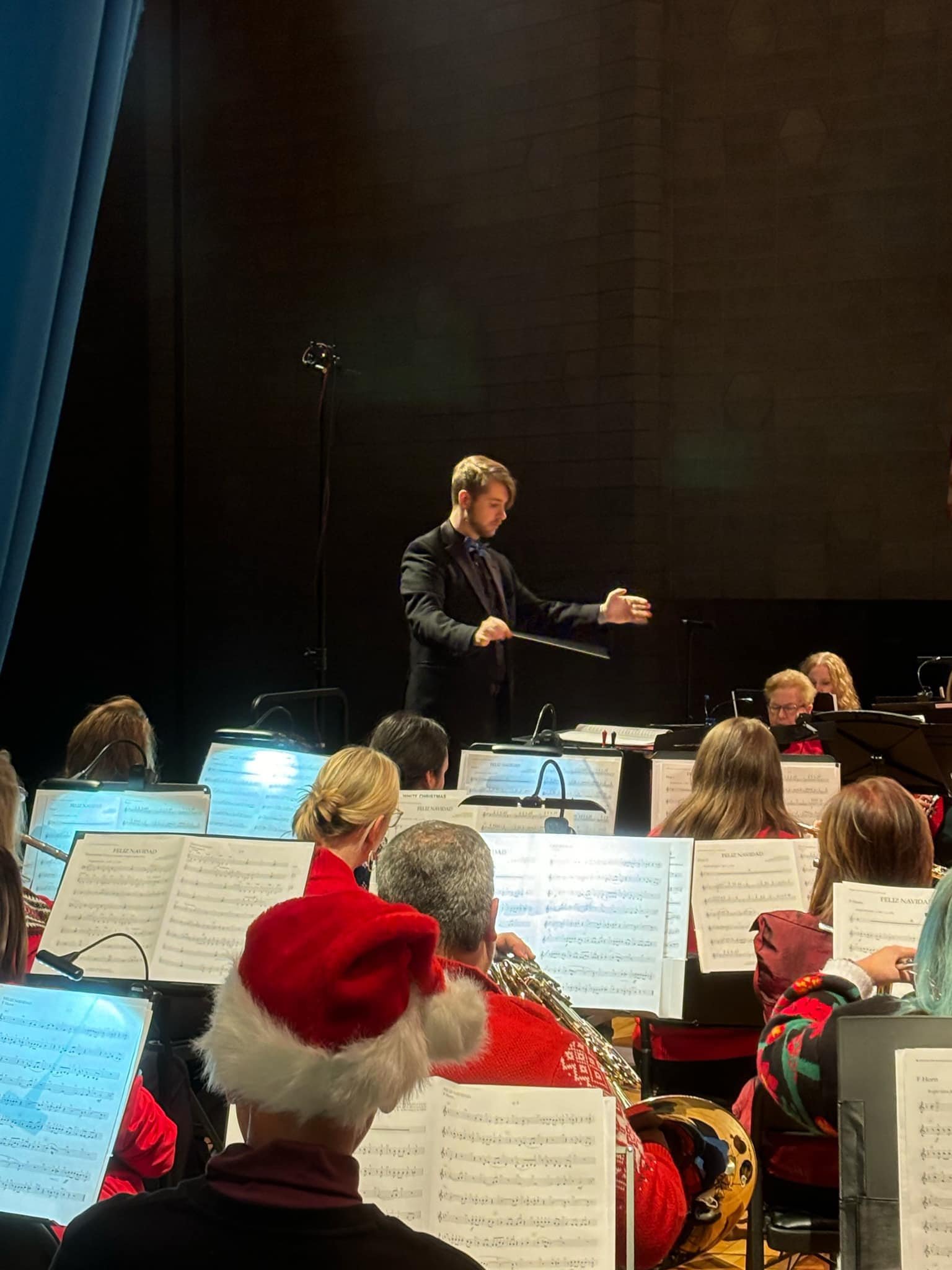 A conductor’s gesture guides BCSWE musicians during a live performance