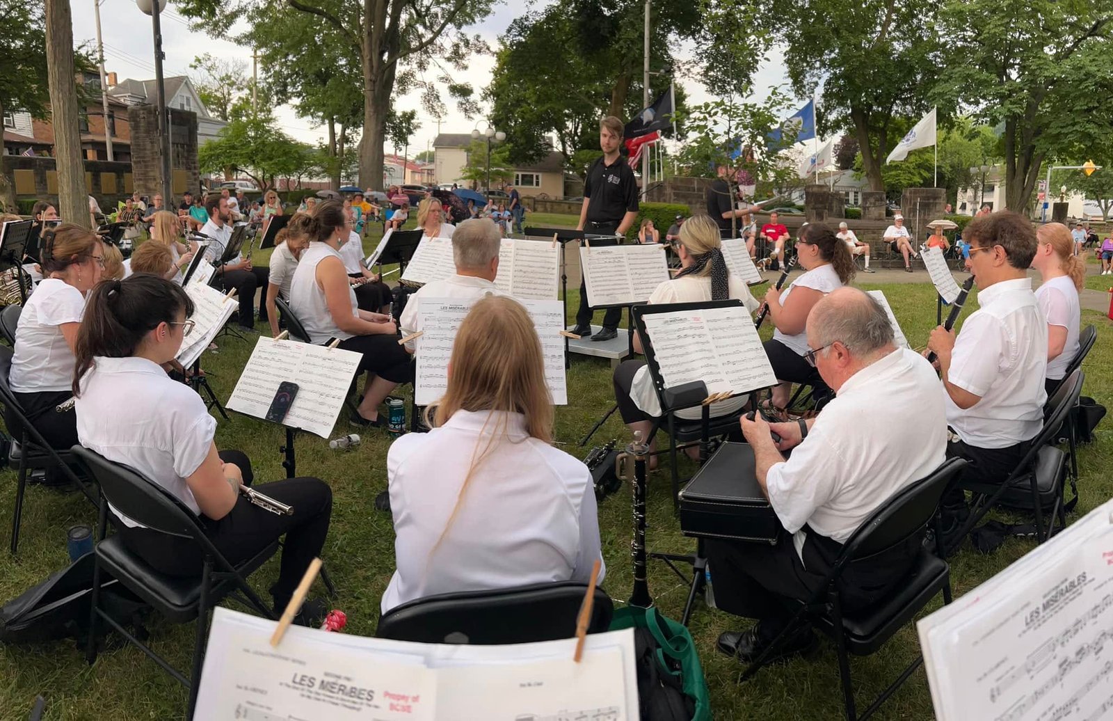 BCSWE musicians and a conductor performing outdoors with listeners nearby