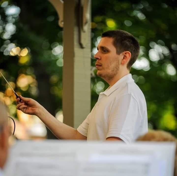 A conductor directing musicians outdoors